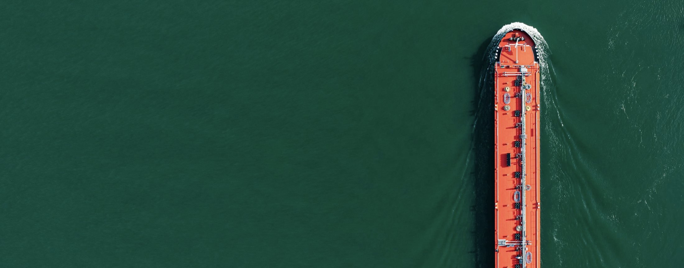 Aerial view of a cargo freighter cruising across open ocean