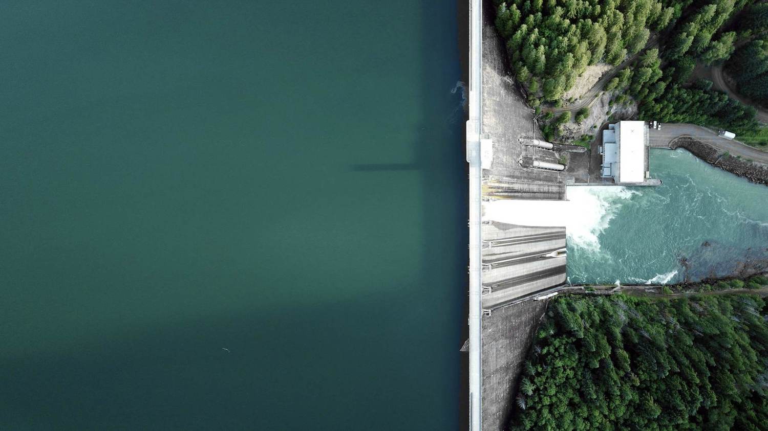 Aerial view of a hydroelectric dam with calm reservoir water and forest