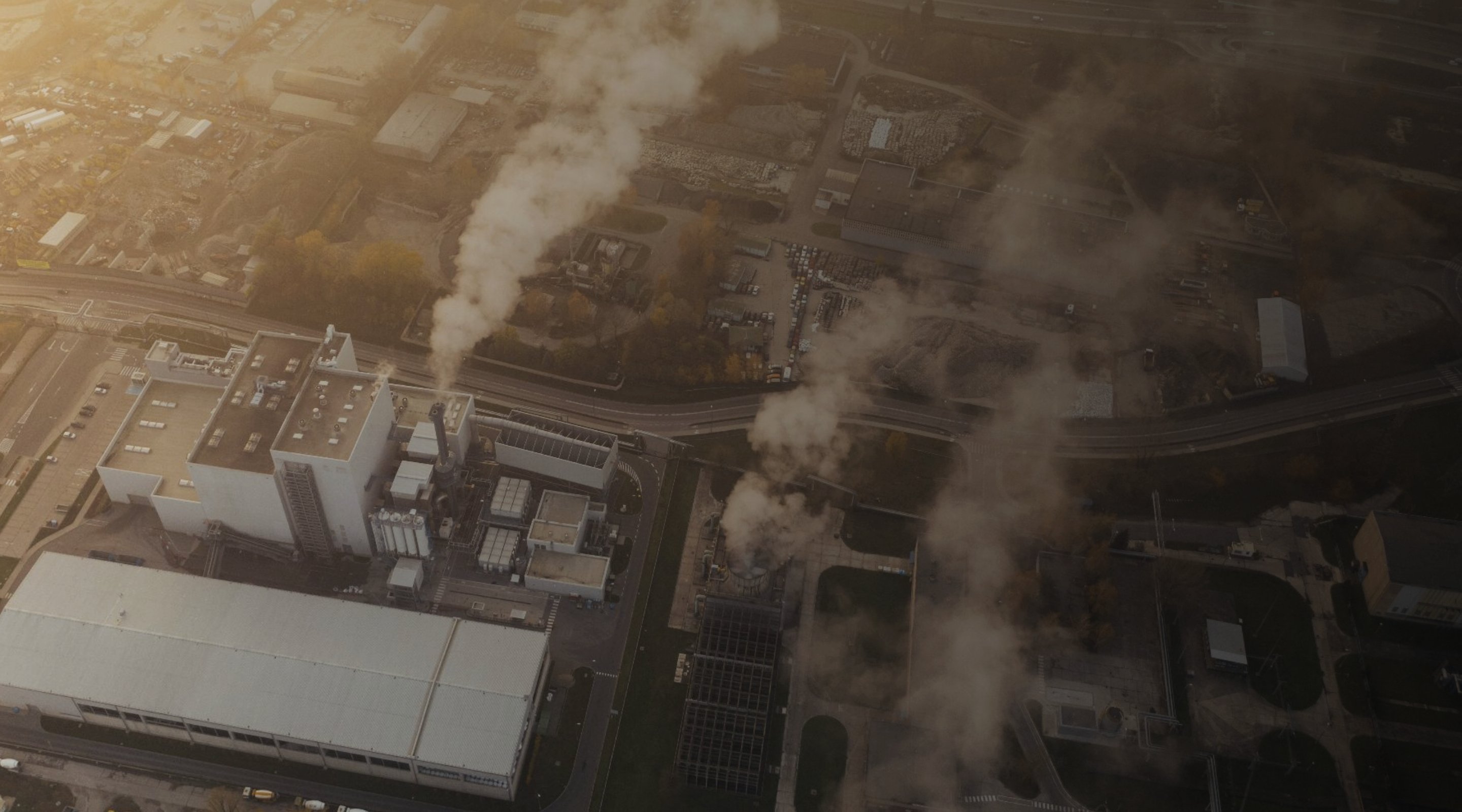 Aerial view of industrial facility smokestacks releasing emissions at dusk