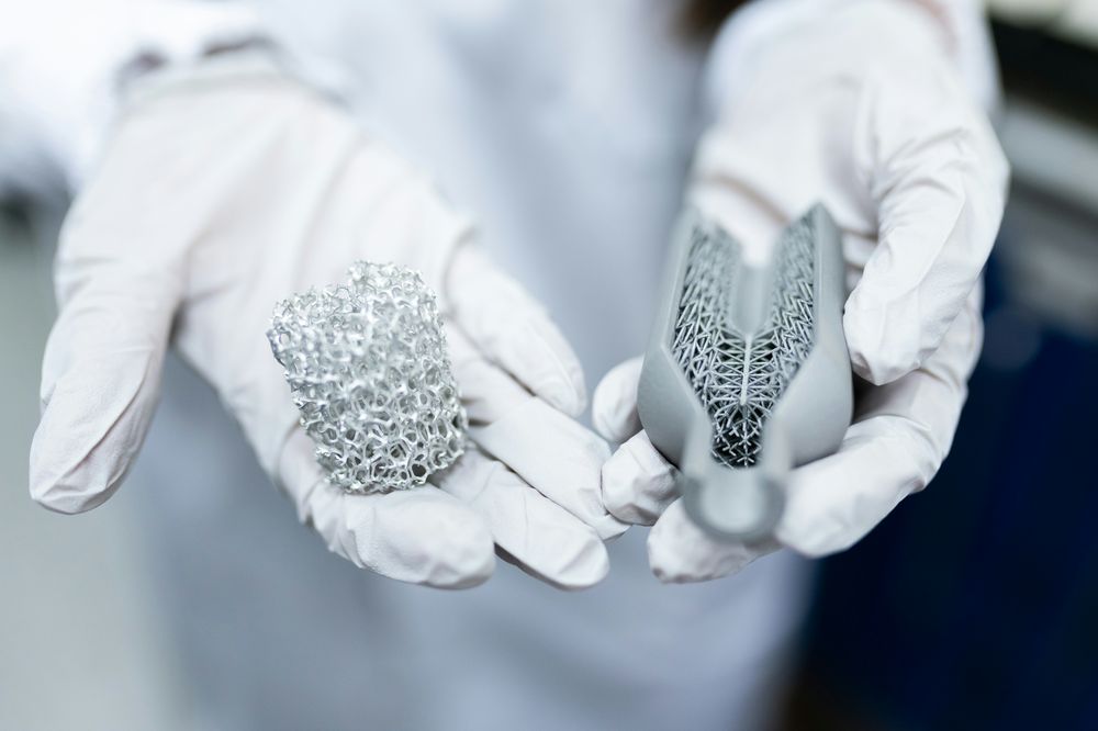 Gloved hands holding precision 3D-printed metal components