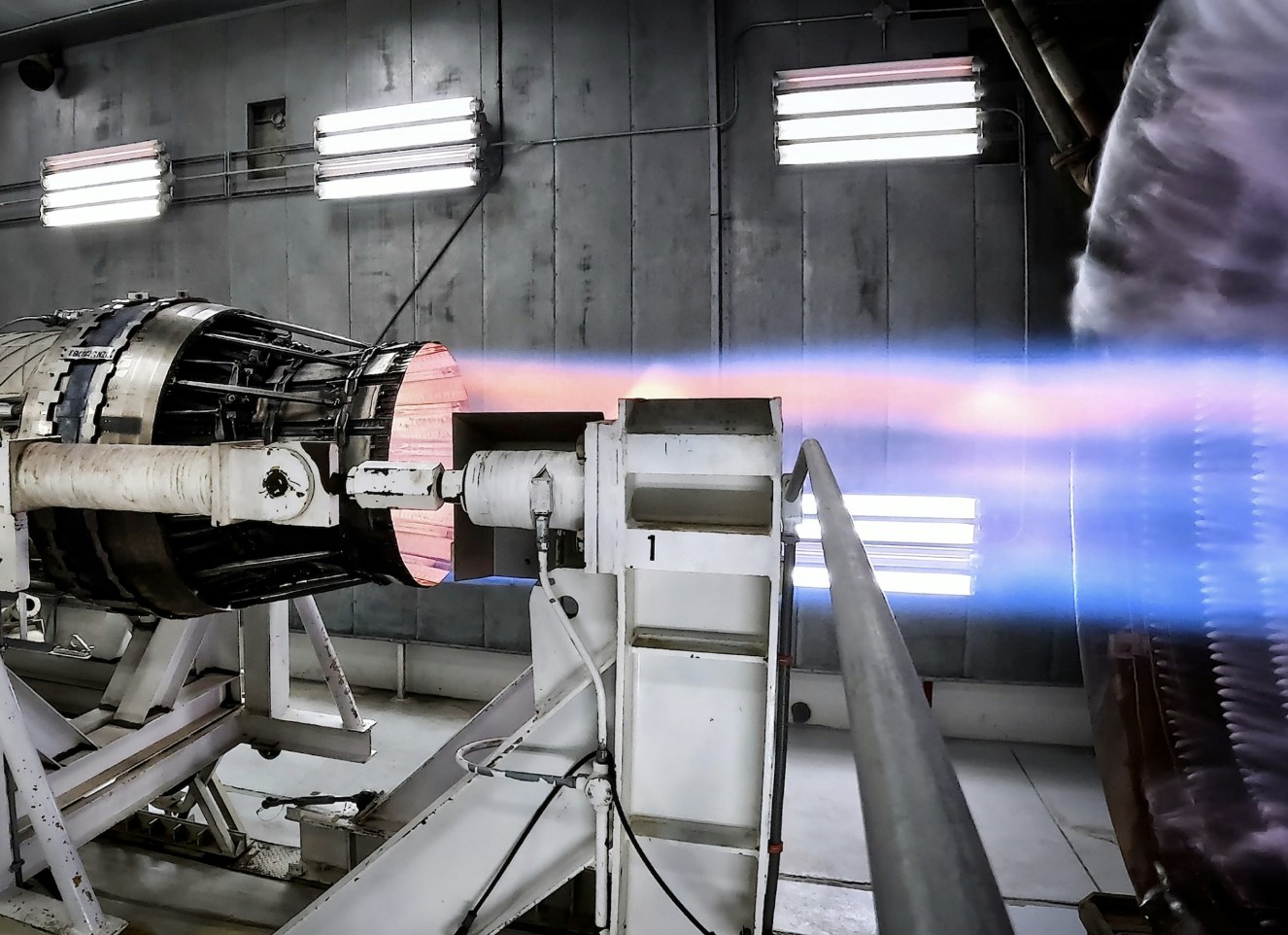 Jet engine afterburner test in an industrial test facility, flame and exhaust extending from the engine nozzle