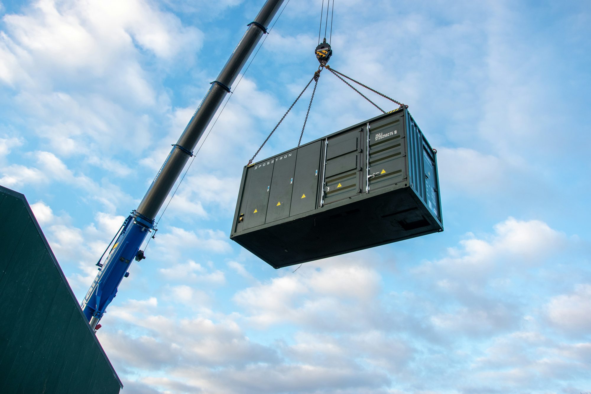 Shipping-container-based system being lifted by crane