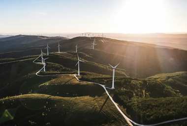 Wind turbines across rolling hills at sunrise